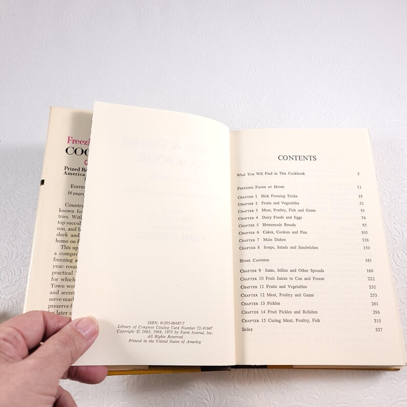 May include: A vintage cookbook titled "Freezing & Cooking" with a yellow spine and a white cover. The cover features the text "Prized Recipes from American Kitchens" and "Every Country Knows... What top success tries. Will you succeed?" The book has a contents page with chapter titles such as "Freezing Foods at Home", "Jams, Jellies and Other Spreads", and "Fruit Pickles and Relishes".