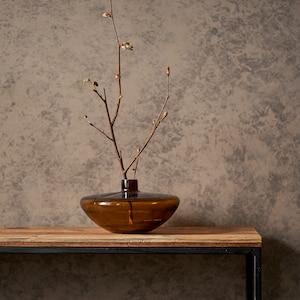 An elegant console made from old boards and a thin square pipe. A rectangular, powder-coated metal frame supports a wooden tabletop made from reclaimed planks. the thin tabletop has a unique pattern of old pine boards.