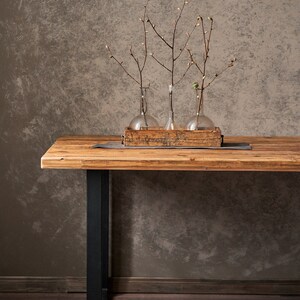 Dining table made of reclaimed pine boards and steel u-shaped legs. The durable metal legs are powder-coated black. The tabletop made from old boards has a pattern that reflects the antiquity and uniqueness of the product.