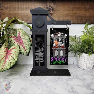 Puede incluir: Un letrero de madera negro con un tema de Halloween espeluznante. El letrero presenta un esqueleto sosteniendo un letrero que dice "Cotton Candy" y un letrero que dice "Spooky Season".