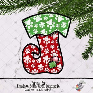 May include: Red and green Christmas stocking with a paw print pattern. The stocking has a green cuff with white paw prints and a red body with white paw prints. There is a small green and red patch on the stocking.