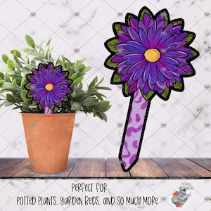 Peut inclure: Un piquet de jardin en forme de fleur violette et jaune avec une tige décorative. Le piquet est à côté d'une plante en pot avec un motif floral similaire. Le texte en bas se lit "Perfect for potted plants, garden beds, and so much more."