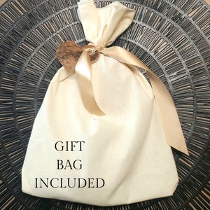 May include: A white cotton gift bag with a brown heart-shaped tag and a gold ribbon. The bag has the text "GIFT BAG INCLUDED" printed on it.
