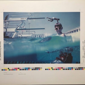 Peut inclure: Un garçon portant des lunettes de soleil regarde l'appareil photo debout dans une piscine. Une personne plonge d'un plongeoir en arrière-plan. L'image est divisée en deux, la moitié supérieure montrant la scène au-dessus de l'eau et la moitié inférieure montrant la scène sous l'eau.