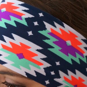 May include: A navy blue headband with a white background and a colourful geometric pattern. The pattern features bright orange, purple, and teal colours.