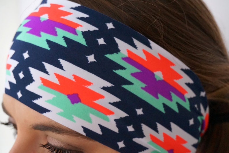 May include: A navy blue headband with a white background and a colourful geometric pattern. The pattern features bright orange, purple, and teal colours.