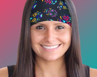 May include: A black headband with a colorful sugar skull pattern. The headband is worn by a person with long dark hair.
