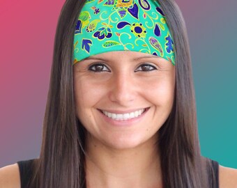 May include: A woman with long brown hair is wearing a teal headband with a colorful paisley pattern. The headband is made of a soft, stretchy material and is perfect for keeping hair out of the face.