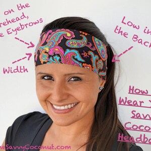 May include: A woman wearing a black and pink paisley patterned headband. The headband is positioned low on the forehead, above the eyebrows, and low at the back. The text "How To Wear Your Savvy Coconut Headband!" is written in pink on a white background.
