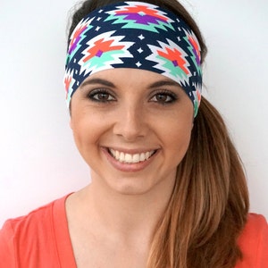 May include: A woman with long brown hair is wearing a headband with a colourful geometric pattern. The headband is navy blue, white, orange, green, and purple.