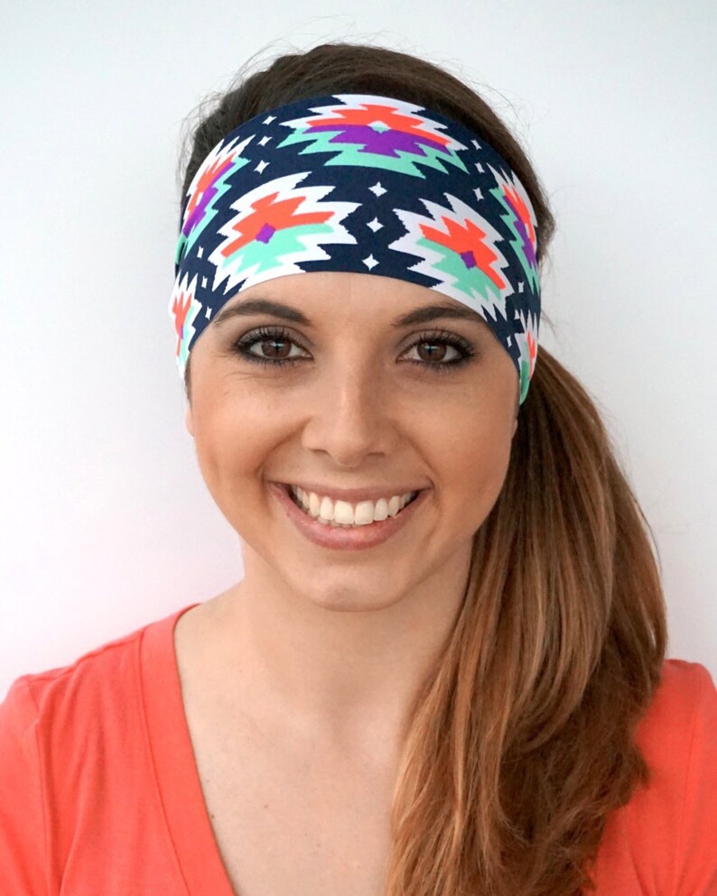 May include: A woman with long brown hair is wearing a headband with a colourful geometric pattern. The headband is navy blue, white, orange, green, and purple.