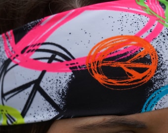 May include: White headband with a black, neon pink, neon green, neon orange, and blue peace sign pattern.
