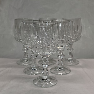 May include: Set of six clear glass wine glasses with a cut crystal design. The glasses have a tall, slender stem and a round bowl.