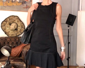May include: A black sleeveless dress with a ruffled hem and white stitching detail. The dress is fitted and has a scoop neck.