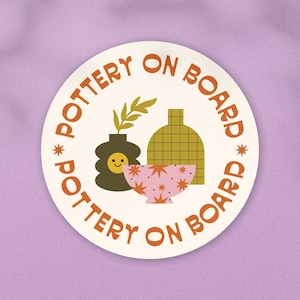 May include: A white round sticker with the text "*POTTERY ON BOARD* POTTERY ON BOARD" in orange lettering. The sticker features a stylized illustration of a pink bowl with orange stars, a green vase with a smiley face, and a yellow grid patterned vase with a green stem.