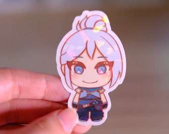 Puede incluir: Una pegatina holográfica con un personaje de dibujos animados con cabello blanco, ojos azules y una diadema roja. El personaje lleva un atuendo azul y negro y sonríe.