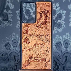 Peut inclure: Coque de téléphone en bois avec un motif gravé au laser. Le motif représente une scène religieuse squelettique détaillée avec du texte latin en bas. La coque a un bord bleu foncé et une découpe pour l'appareil photo du téléphone.