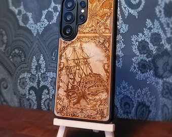 May include: Wooden phone case featuring a detailed engraving of a ship being attacked by a giant kraken. The design is in a light brown color, with the text "Below the thunder, the Kraken wails". The case has a black border and a camera cutout.