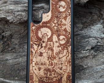 Puede incluir: Una funda de teléfono negra con un diseño de veta de madera que presenta un grabado detallado de una nave espacial y una luna. El diseño es intrincado e incluye patrones florales.