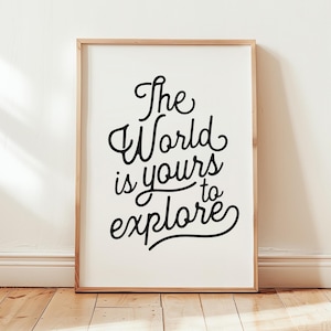May include: A rectangular wall art print in a light wood frame featuring the black cursive text The World is yours to explore centered on a white background. The lettering is stylized with flowing lines and loops, creating a clear message.