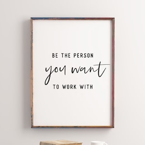 Könnte beinhalten: Ein gerahmter Druck mit weißem Hintergrund und schwarzem Text, der "Sei die Person, mit der du arbeiten möchtest" lautet. Der Rahmen ist aus verwittertem Holz mit blauer, roter und brauner Farbe.