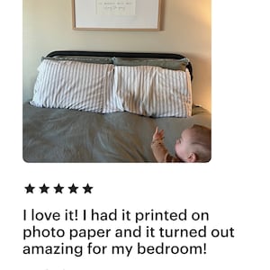 May include: A framed print with the text "The best things in life are the people we love, the places we've been, and the memories we've made along the way." The print is hanging on a wall above a bed with two pillows and a baby lying on the bed.