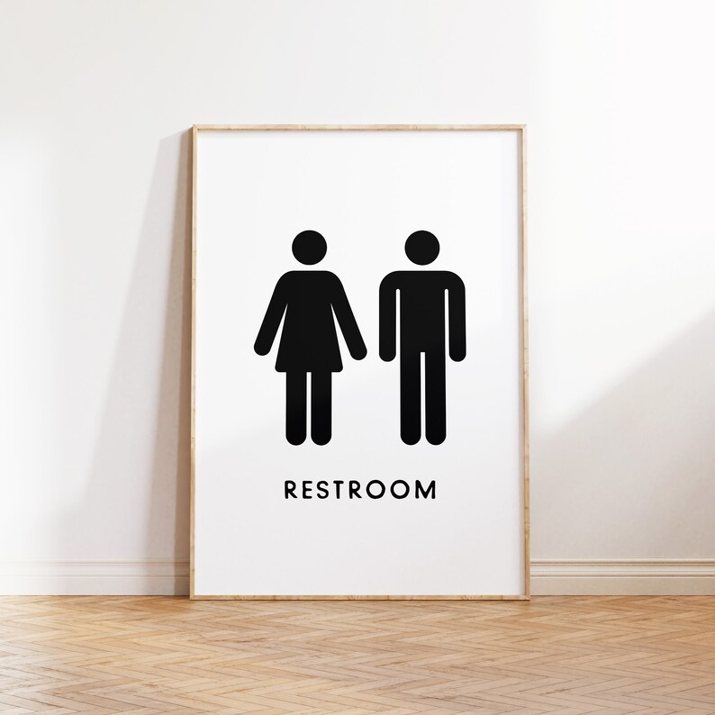 May include: Black and white restroom sign with the word "RESTROOM" printed below two stick figures, one with a skirt and one without.