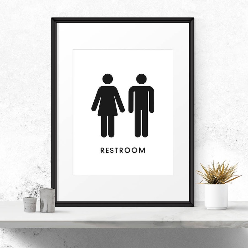 May include: Black and white restroom sign with a stylised male and female figure. The sign reads "RESTROOM".