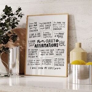 May include: A framed print with the words "Mom Daily Affirmations" in black script. The print includes positive affirmations for mothers, such as "I am the best mom for my children" and "I will show my kids love."