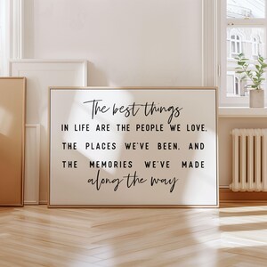 May include: A black and white inspirational quote on a framed canvas with a gold frame. The quote reads: "The best things in life are the people we love. The places we've been. And the memories we've made along the way."