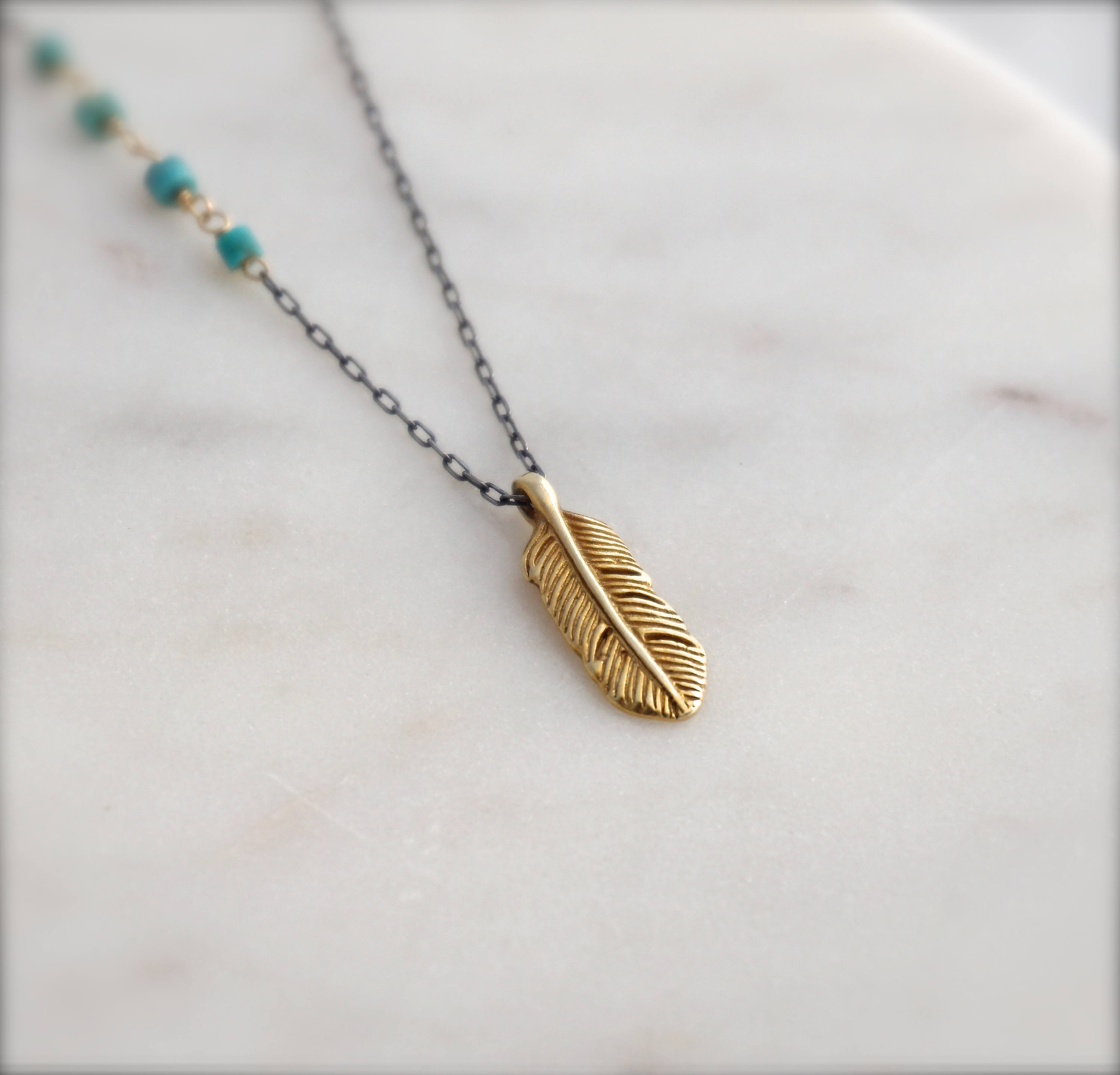 Little golden feather on black chain