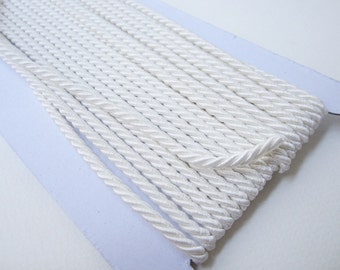 Puede incluir: Cordón trenzado blanco, un tipo de adorno decorativo utilizado para coser y proyectos de manualidades.