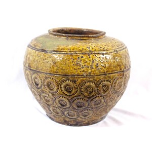 May include: A brown and yellow ceramic jar with a circular pattern. The jar has a wide mouth and a rounded body.