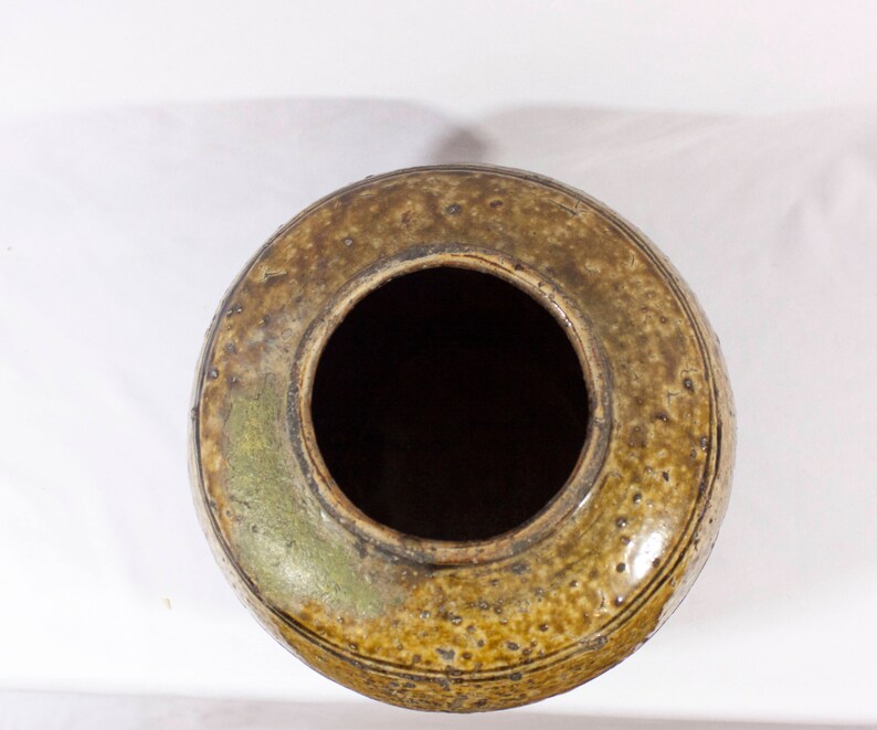 May include: A brown ceramic pot with a wide opening and a textured surface. The pot has a dark brown glaze with a speckled pattern.