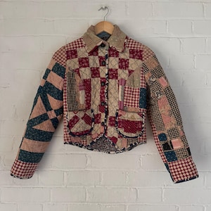 May include: A vintage quilted jacket with a patchwork design in shades of red, pink, blue, and white. The jacket has a button-up front and a collar.