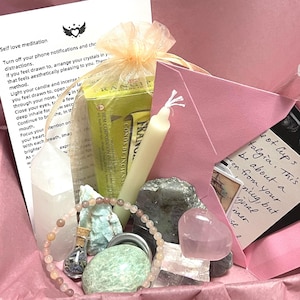 Puede incluir: Una caja de regalo rosa llena de cristales, incienso, una vela y una pulsera de cuentas. La caja contiene varios cristales, un pequeño sobre rosa y una tarjeta con texto manuscrito. Medidas en cm y gramos.