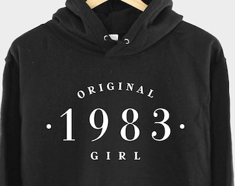 Pode incluir: Camisola de moletom com capuz preta com texto branco que diz "ORIGINAL . 1983 . GIRL"