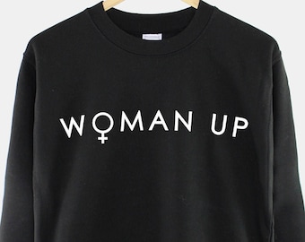 May include: Black sweatshirt with the text "WOMAN UP" in white lettering and a female symbol.