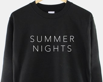 以下が含まれることがあります： 前面に白い文字で「SUMMER NIGHTS」とプリントされた黒いスウェットシャツです。