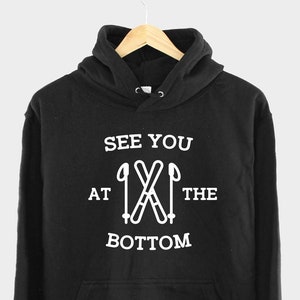 May include: Black hooded sweatshirt with white text that reads "See you at the bottom" with a graphic of crossed ski poles.