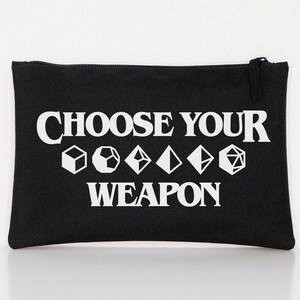Può includere: Pochette nera in tela con cerniera con testo bianco che recita "Choose Your Weapon" e una fila di cinque simboli di dadi bianchi.