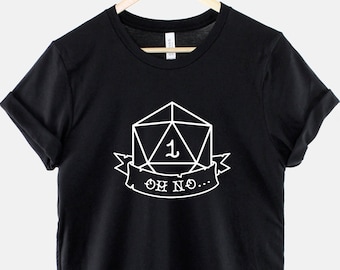 May include: Black t-shirt with a white graphic of a twenty-sided die with a one showing and a banner that reads "Oh No..."