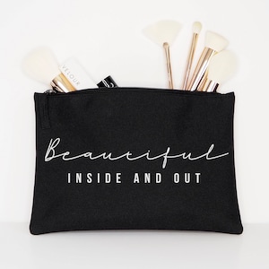 May include: Black canvas makeup bag with a zipper closure. The bag has white text that reads "Beautiful Inside and Out".