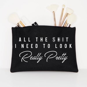 May include: Black zippered makeup bag with the text "ALL THE S**T I NEED TO LOOK Really Pretty" printed in white.