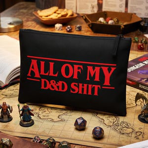 Op de afbeelding: Een zwart rechthoekig etui met ritssluiting en de rode tekst ALL OF MY D&D SHIT op de voorzijde. Het etui is gemaakt van een gladde stof en is voorzien van een zwarte ritssluiting aan de bovenrand om de inhoud veilig in op te bergen.