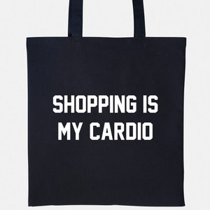 May include: A black tote bag with white text that reads "SHOPPING IS MY CARDIO".
