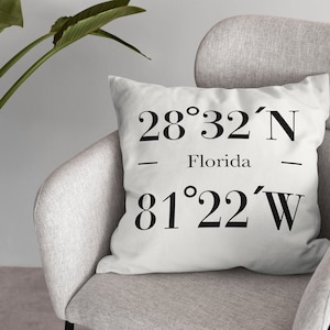 May include: White cushion with black text that reads "28°32'N - Florida - 81°22'W".