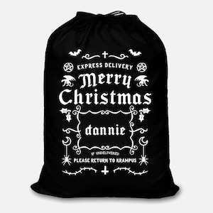May include: Black Christmas gift bag with white text that reads "Express Delivery Merry Christmas dannie If Undelivered Please Return to Krampus". The bag has a drawstring closure and is decorated with bats, pentagrams, and other gothic imagery.