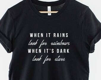 May include: Black t-shirt with white text that reads "WHEN IT RAINS look for rainbows WHEN IT'S DARK look for stars"