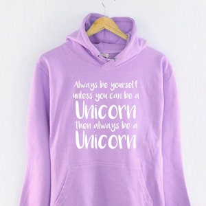 May include: A lavender hoodie with a white graphic that reads "Always be yourself unless you can be a Unicorn then always be a Unicorn."